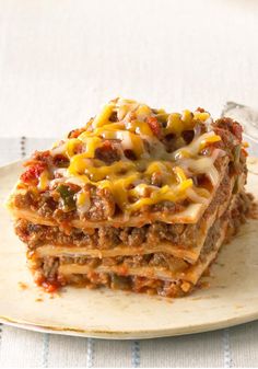 a stack of lasagna casserole on a white plate with a fork