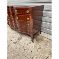 three wooden dressers sitting next to each other in front of a metal garage door