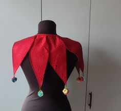 a mannequin wearing a red scarf with tassels and beads on it