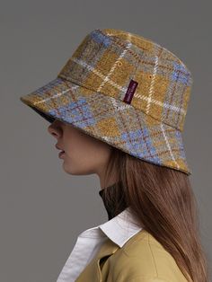 a woman wearing a yellow coat and a brown hat with plaid pattern on the brim