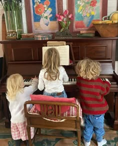 two young children playing piano in front of an old piano