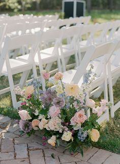 a bunch of white chairs with flowers on them