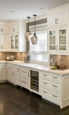 a kitchen filled with lots of white cabinets and counter top space next to a window