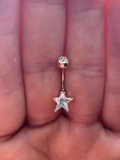 a person's hand holding an open ring with a star on it