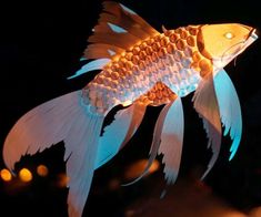 a paper fish is lit up in the dark with lights on it's sides