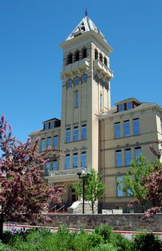 a tall building with a clock on the top of it's tower and trees in front of it