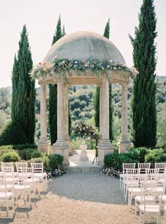 an outdoor ceremony setup with white chairs and flowers