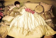 a woman laying on top of a bed covered in pillows