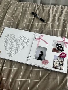 an open book with pink ribbon and pictures on it sitting on top of a bed