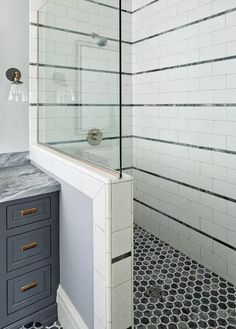 a bathroom with black and white flooring and tile on the walls, along with a walk in shower