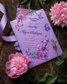 a purple wedding card with pink flowers and butterflies on it next to some green leaves