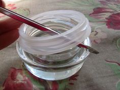 a person is holding a paintbrush and painting the inside of a jar with water