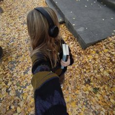 a girl with headphones is holding something in her hand and looking at the ground