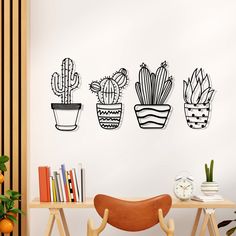 three potted cacti are on the wall next to a wooden table and chair