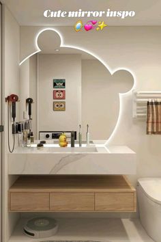 a bathroom with a sink, toilet and mirror that has mickey ears on the side