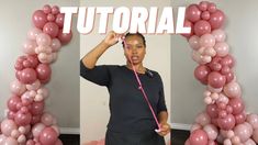 a woman standing in front of a pink balloon arch