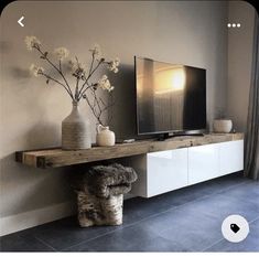 a living room with a large tv on top of a wooden shelf