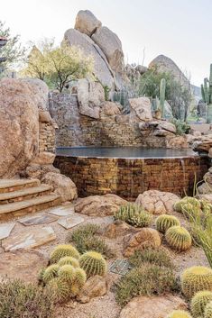 an outdoor hot tub surrounded by rocks and cacti