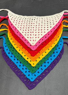 a multicolored crocheted triangle is sitting on the floor with it's sides folded up