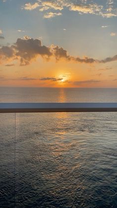 the sun is setting over the ocean with clouds