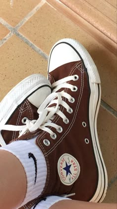 a person wearing brown and white converse shoes