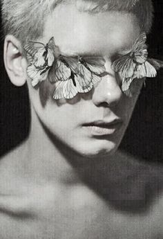 a young man with butterflies on his face and chest is shown in black and white