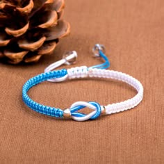 a blue and white bracelet with an arrow on it next to a pinecone