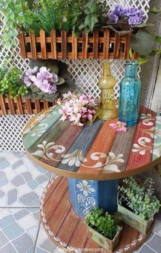 a colorful table with flowers and vases on it in front of a white fence