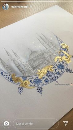 an image of a drawing on paper with gold and blue designs in the middle, sitting on top of a wooden table