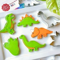 cookies decorated with green and orange icing sitting on a tray next to cookie cutters