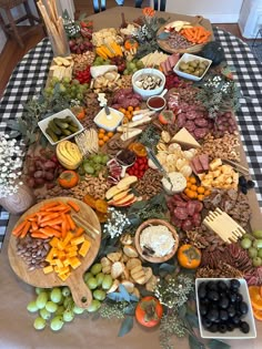 a table topped with lots of different types of cheese and crackers on top of a checkered table cloth