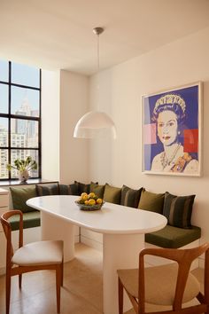 a white table sitting in front of a window next to a green couch and two chairs