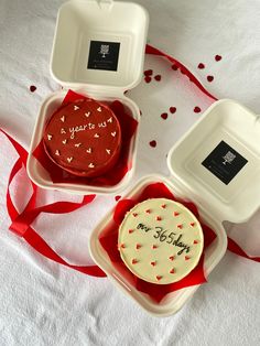 three plastic containers with decorated cookies in them on a white tablecloth and red streamers