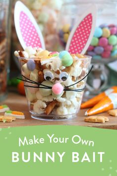 a glass filled with candy and bunny ears on top of a table next to carrots