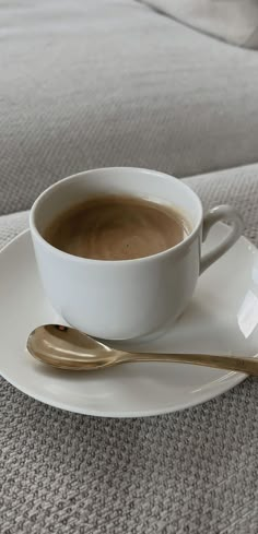 a cup of coffee sitting on top of a white saucer with gold spoons