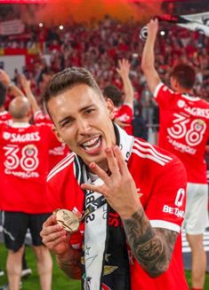 a soccer player is holding up his gold medal in front of the crowd at a sporting event