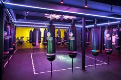 an indoor boxing gym with punching bags and neon lights on the ceiling, all lit up