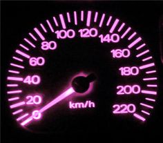 a close up of a speedometer in the dark with pink lights and numbers on it