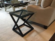 a glass table sitting on top of a white carpeted floor next to a couch