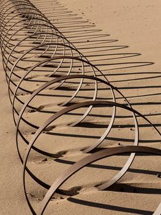 a row of curved metal bars sitting on top of a sandy beach