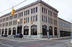 an old building on the corner of a street with traffic lights and cars parked in front