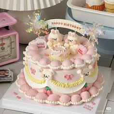 a birthday cake decorated with pink and yellow icing, topped with three little pigs