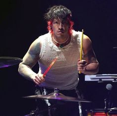 a man with red hair holding a drumstick in front of a drum set on stage