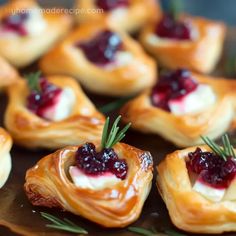 small pastries with cranberry sauce and rosemary sprigs on a tray