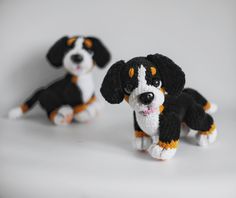 two black and white dogs sitting next to each other on a white surface with one dog looking at the camera