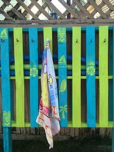 an umbrella sitting on top of a blue and green bench next to a wooden fence