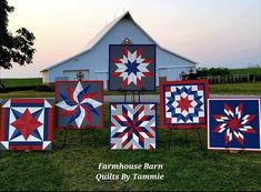 several quilts on display in front of a barn