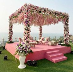 an outdoor ceremony setup with pink and white flowers on the stage, steps leading up to it