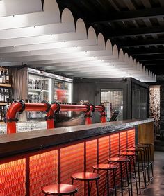 an empty bar with red chairs and bars