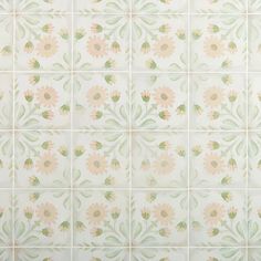 a white tiled wall with pink and green flowers on it